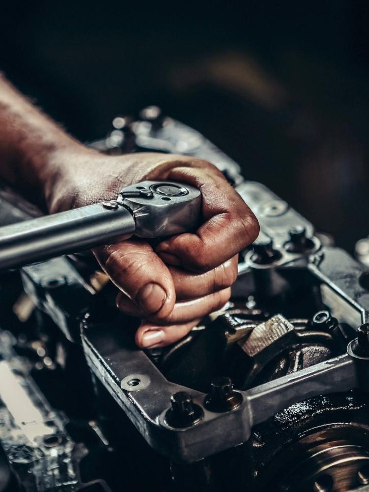 Mecânico a reparar um motor de automóvel com chave de roquete